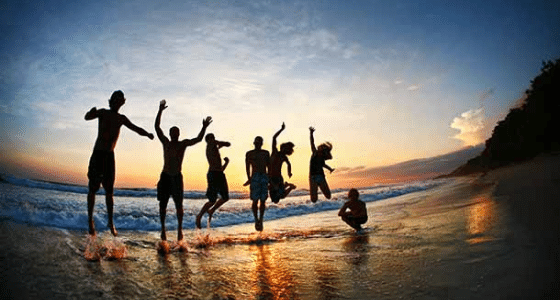 Students jumping on sunset beach