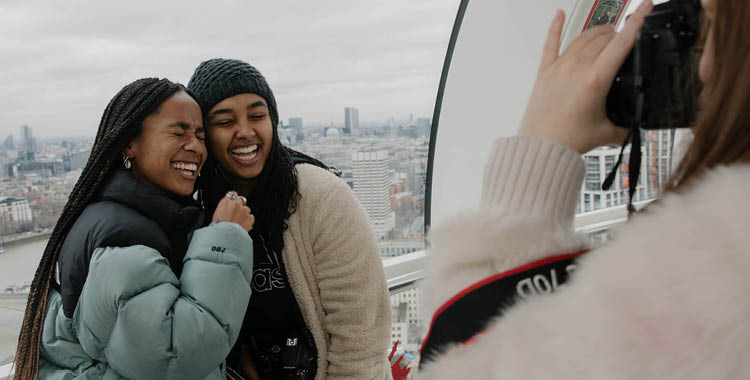 Two students laugh while they have their photo taken by a third person in London, England. 