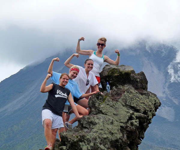 Four students flex their arms while climbing a mountain in Costa Rica.