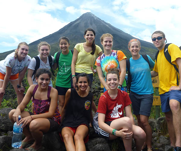 A group of students pose in front of Arenal Volcano in Costa Rica.