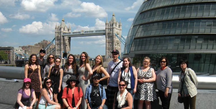 A large group of students pose in front of London Bridge in London, England.