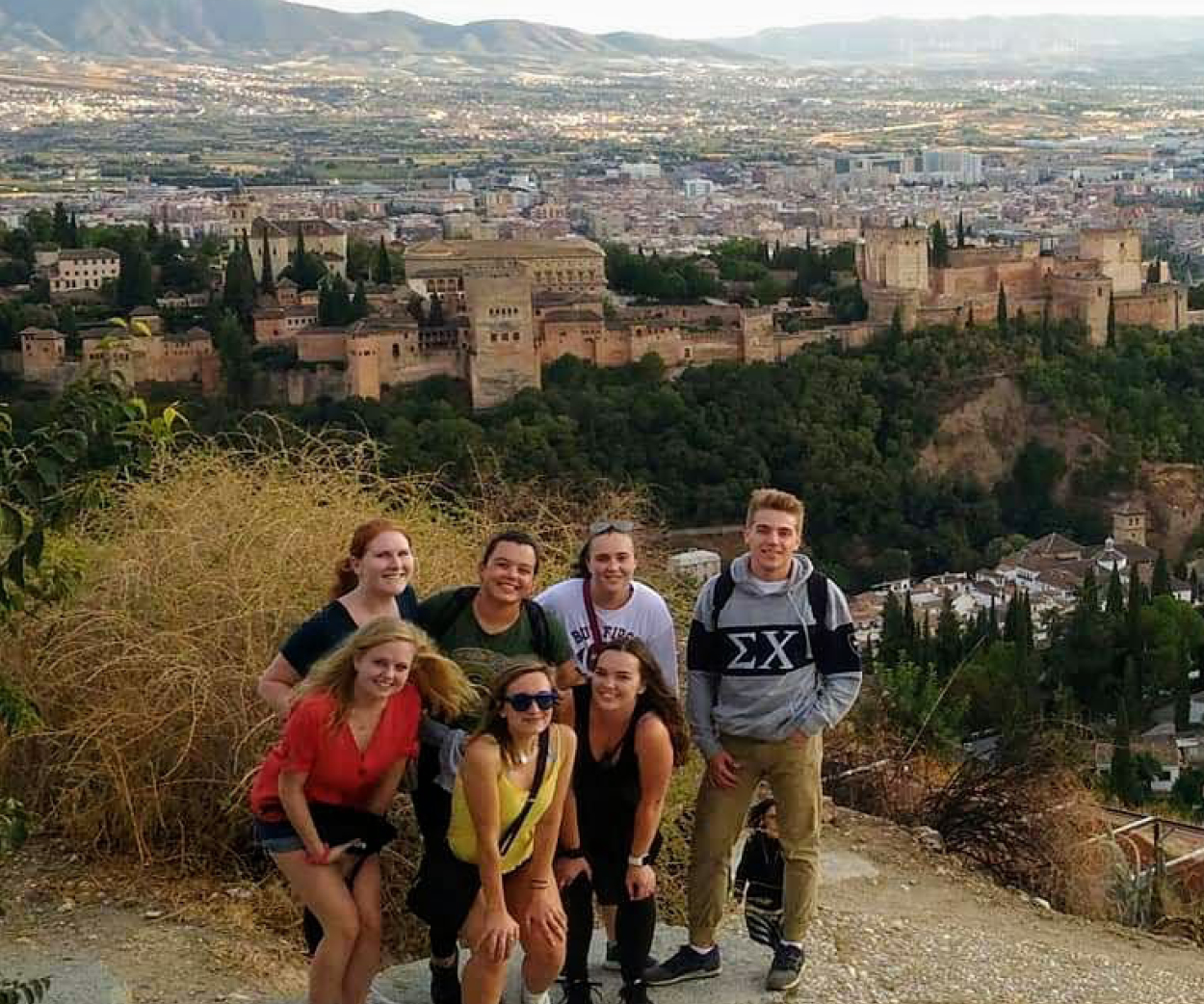 Seven students pose on a hill overlooking Granada, Spain.